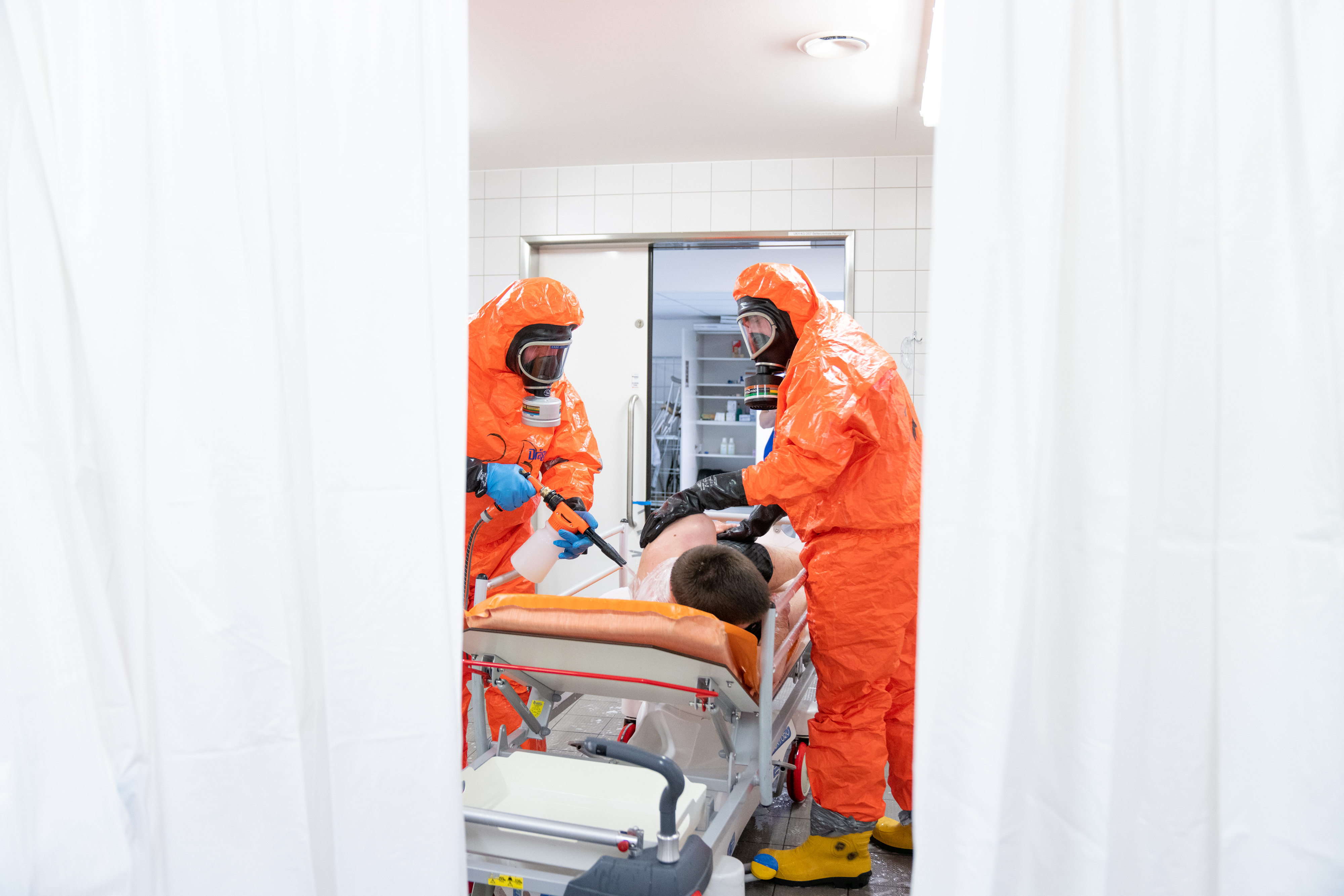 Mitarbeiter:innen des Katastrophenschutzes reinigen/dekontaminieren einen Patienten.