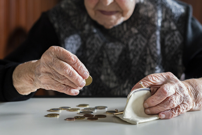 Ältere Frau zählt Münzen am Kücehntisch