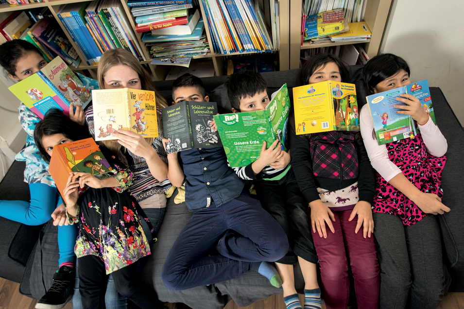 LernLEO - Kinder liegen auf Sofa und verdecken sich das Gesicht mit Büchern